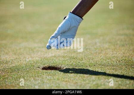 Nahaufnahme der Handschuhhand, die den Golfball aus dem Loch nimmt, Kopierbereich Stockfoto