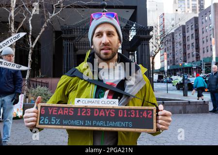 New York, New York, USA. 21. März 2023. Dritter Akt, die soziale Aktivistenbewegung älterer Menschen, sponserte eine Kundgebung gegen Bankinvestitionen in fossile Brennstoffe, die am Dag Hammerskjöld Plaza begann und in die 47. Straße zum Hauptsitz von J. P. Morgan Chase zog. Ein Mann hat eine digitale Klimauhr, die 6 Jahre, 123 Tage, 1 Stunde, 31 Minuten und 42 Sekunden anzeigt. Kredit: Ed Lefkowicz/Alamy Live News Stockfoto