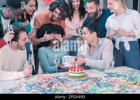 Gruppe glücklicher, multiethnischer Menschen, die unter Freunden Geburtstag feiern und während einer Party lächeln. Überraschung für das Geburtstagskind Stockfoto