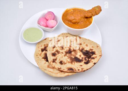 Butterhähnchen mit Tandoori Roti, serviert mit eingelegten Zwiebeln und Minzchutney in einem auf weißem Hintergrund isolierten Teller Stockfoto