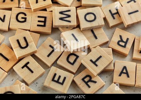 Ein Haufen Holzfliesen mit verschiedenen Buchstaben, die auf einem weißen Stein verstreut sind, wie ein Brett, Nahaufnahme von oben Stockfoto