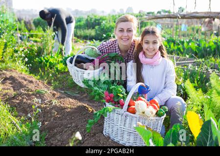 Eine Farmerin und ihre Tochter im Teenageralter halten einen Weidenkorb in der Hand Stockfoto