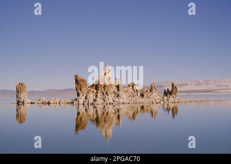 Ein großer Felsbrocken aus dem kristallklaren Wasser eines ruhigen Sees Stockfoto