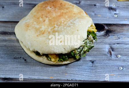 Flat Shami Syrian Bread gefüllt mit pommes Frites und grünem Salat, traditionelle ägyptische frittierte Kartoffeln Finger Sandwich umgeben von kühlen und knusprigen umgeben Stockfoto