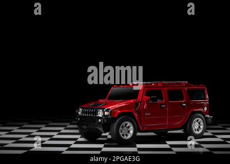 Izmir, Türkei - 15. März 2023. Roter Hummer H2 4x4 Geländefahrzeug auf kariertem Boden und schwarzem Hintergrund. Stockfoto