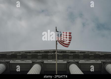 Eine Nahaufnahme des Haupteingangs zum Rathaus mit der US-Nationalflagge, die eine große Reihe von Stufen zu den Haupttüren des Gebäudes bietet. Die Stufen sind von Palmen und anderen üppigen Vegetationen gesäumt, was die Pracht und Schönheit des Gebäudes noch verstärkt. Nach zwei Jahren Renovierung hat das berühmte Rathaus von San Francisco seit Juni 2021 endlich wieder seine Türen für die Öffentlichkeit geöffnet. Das Projekt im Wert von $550 Millionen Dollar zielte darauf ab, die historischen Elemente des Gebäudes wiederherzustellen und es gleichzeitig zu modernisieren, um den Bedürfnissen des 21. Jahrhunderts gerecht zu werden. Das Projekt umfasste die Restaurierung der berühmten Kuppel des Rathauses, w Stockfoto