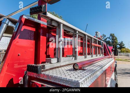 Die stabile Schiebeleiter ist seitlich am roten Feuerwehrwagen fest befestigt. Stockfoto