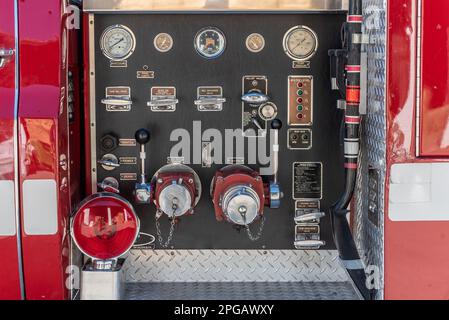 Die Nahaufnahme des hinteren Feuerwehrwagens verfügt über Bedienelemente für Entleerung, Ablass, Tankfüllung, Überdruckventil und Saugventil, die sich alle auf einer Tafel befinden. Stockfoto
