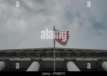 Kalifornien, San Francisco, USA. 20. März 2023. Eine Nahaufnahme des Haupteingangs zum Rathaus mit der US-Nationalflagge, die eine große Reihe von Stufen zu den Haupttüren des Gebäudes bietet. Die Stufen sind von Palmen und anderen üppigen Vegetationen gesäumt, was die Pracht und Schönheit des Gebäudes noch verstärkt. Nach zwei Jahren Renovierung hat das berühmte Rathaus von San Francisco seit Juni 2021 endlich wieder seine Türen für die Öffentlichkeit geöffnet. Das $550 Millionen Dollar schwere Projekt zielte darauf ab, die historischen Elemente des Gebäudes wiederherzustellen und es gleichzeitig zu modernisieren, um den Bedürfnissen des 21. Jahrhunderts gerecht zu werden. Das Projekt Stockfoto
