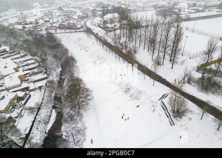 Luftaufnahme von Personen, die während eines Schneesturms auf Schlitten spielen (Ebbw Vale, Wales) Stockfoto