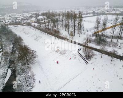 Luftaufnahme von Personen, die während eines Schneesturms auf Schlitten spielen (Ebbw Vale, Wales) Stockfoto