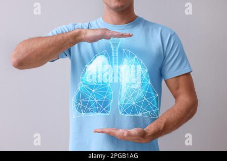 Mann, der Hände nahe der Brust hält, mit Darstellung der Lungen auf grauem Hintergrund, Nahaufnahme Stockfoto