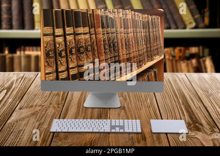 Online-Bibliothek. Moderner Computer auf Holztisch und Regalen mit Büchern im Innenbereich Stockfoto