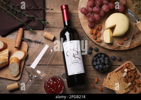 Flasche Rotwein mit Glas und Vorspeisen auf Holztisch, flach liegend Stockfoto