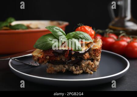 Teller mit leckerer Auberginen-Lasagne serviert auf schwarzem Tisch, Nahaufnahme Stockfoto