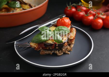 Teller mit leckerer Auberginen-Lasagne serviert auf schwarzem Tisch, Nahaufnahme Stockfoto