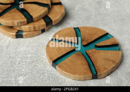 Stilvolle Untersetzer mit Holzbechern auf hellgrauem Tisch Stockfoto