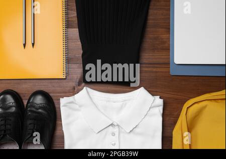 Stilvolle Schuluniform und Schreibwaren auf Holzhintergrund, flach liegend Stockfoto