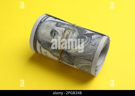 Gerollte Dollarscheine auf gelbem Hintergrund, Nahaufnahme. Amerikanische Landeswährung Stockfoto