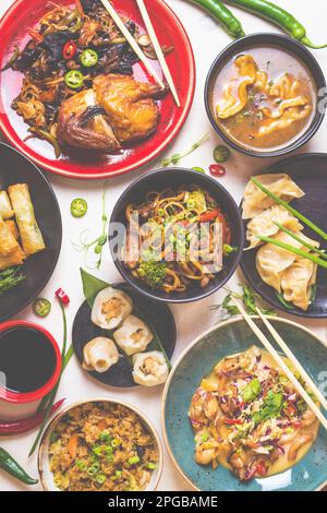 Gemischtes chinesisches Essensset. Chinesische Nudeln, gebratener Reis, Teigtaschen, peking-Ente, Dim Sum, Frühlingsrollen. Berühmte chinesische Gerichte auf einem weißen Tisch. Stockfoto