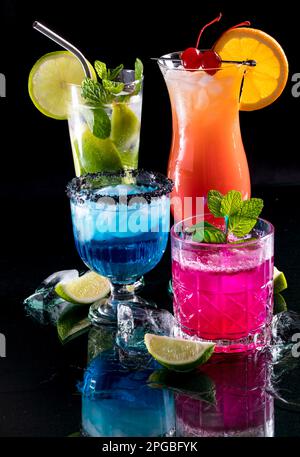 Helle, leuchtende Cocktails, die sich auf Glas vor schwarzem Hintergrund spiegeln Stockfoto