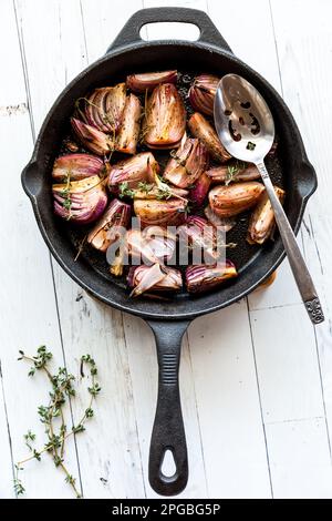 Karamellisierte geröstete rote Zwiebeln in einer gusseisernen Pfanne. Stockfoto