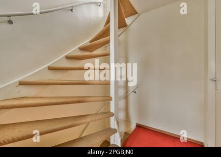 Das Innere eines Hauses mit Holztreppe und rotem Teppich auf dem Boden vor der weißen Tür Stockfoto