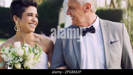 Ich liebe es, dich so glücklich zu sehen. Ein liebevoller, reifer Vater, der seine Tochter anlächelt, während er sie an ihrem Hochzeitstag hinunterführt. Stockfoto