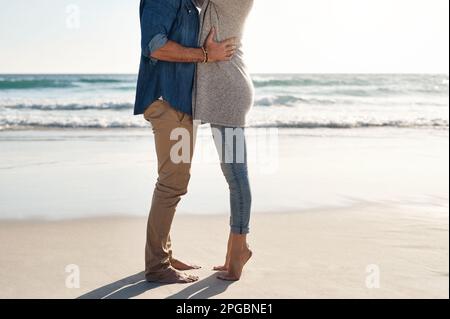 Alles ist großartig, wenn unsere Zehen im Sand sind. Ein unbekanntes Paar, das eine schöne Zeit am Strand verbringt. Stockfoto