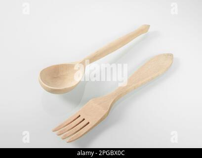 Küchenutensilien aus Holz. Holzlöffel und Gabel auf weißem Spiegelhintergrund. Stockfoto