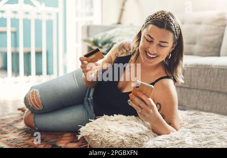 Eine Verabredung zum Mittagessen, nur mit mir. Eine junge Frau, die einen Laptop und eine Kreditkarte in ihrem Wohnzimmer zu Hause benutzt. Stockfoto