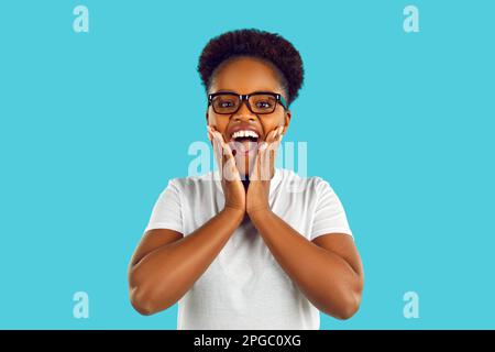 Aufgeregte und glückliche junge afroamerikanische Frau, die auf riesige Angebote und verrückte Rabatte reagiert. Stockfoto