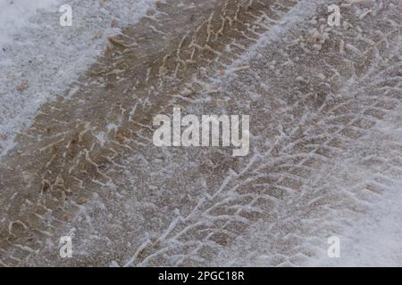 Autospuren auf einer verschneiten Straße. Rutschige Straße, Gefahr, Rutschgefahr. Spuren von Winterreifen. Stockfoto