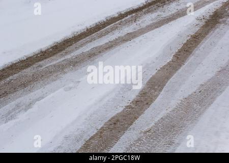 Autospuren auf einer verschneiten Straße. Rutschige Straße, Gefahr, Rutschgefahr. Spuren von Winterreifen. Stockfoto