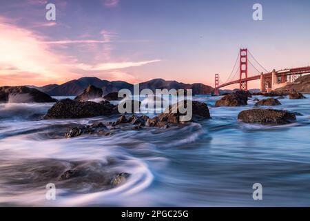 Ein faszinierendes Zeitrafferbild eines Flusses, der durch eine Stadtlandschaft fließt, mit der berühmten Golden Gate Bridge im Hintergrund Stockfoto