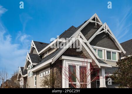 Dachschindeln auf dem Haus vor blauem Himmel. Dunkle Asphaltfliesen auf dem Dachhintergrund. Schwarze Gürtelrose, Dachziegel. Niemand, selektiver Fokus, str Stockfoto