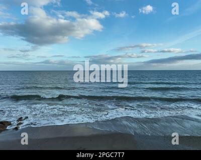 Ein Strand, umgeben von sanften Wolken und einem glitzernden Gewässer Stockfoto