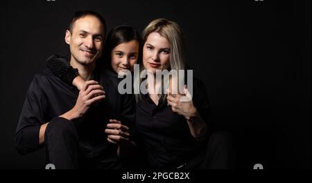 Glückliche junge Familie mit einem Kind, die Spaß zusammen haben, isoliert auf Schwarz.