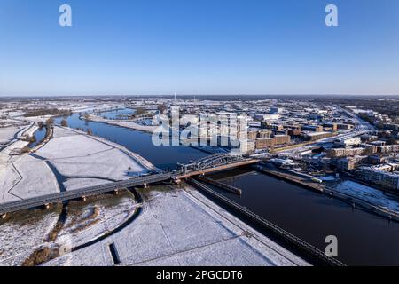 Luftlandschaft nach einem Schneesturm mit Stahlbrücke über den Fluss IJssel und weiße Überschwemmungsebenen der holländischen mittelalterlichen Turmstadt Zutphen Stockfoto