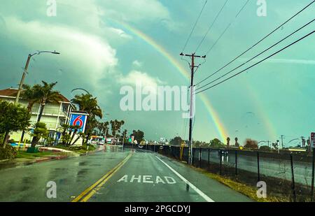 Carpinteria, Kalifornien, USA. 21. März 2023. Auf der Straße steht "voraus", und vor Ihnen liegt das Motel 6 auf der linken Seite und ein Regenbogen auf der rechten Seite, wenn Licht durch die schweren Wolken bricht, nahe Carpinteria, CA. (Kreditbild: © Amy Katz/ZUMA Press Wire) NUR REDAKTIONELLE VERWENDUNG! Nicht für den kommerziellen GEBRAUCH! Stockfoto