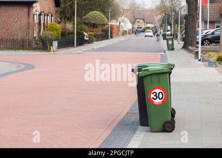 Müllcontainer auf der Straße mit einem geschwindigkeitsbegrenzenden Straßenschild von bis zu 30 km/h. Stockfoto