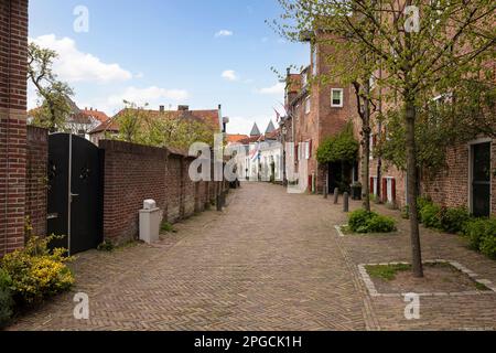 Enge Straße mit holländischen Flaggen im alten mittelalterlichen Zentrum der niederländischen Stadt Amersfoort. Stockfoto