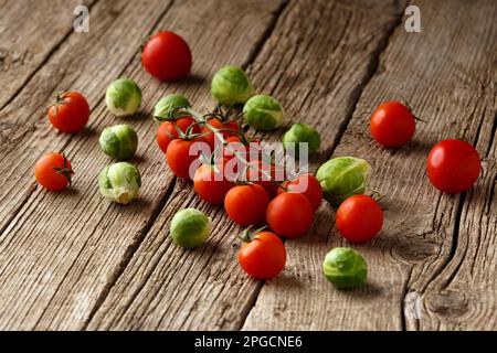 Tomaten, Gurken, Paprika, Rosenkohl auf einem hölzernen Hintergrund von oben. Mischung aus gesundem Gemüse. Rohes Sommergemüse. Ein Symbol für richtig, Stockfoto