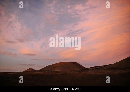 Malerische Landschaft der Gebirgszüge vor dem bewölkten blauen und rosafarbenen Sonnenuntergang am Abend auf Lanzarote Stockfoto