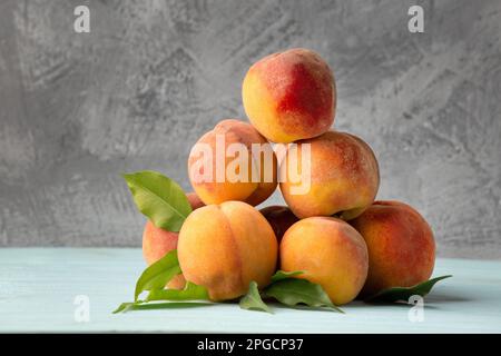Viele Pfirsiche auf grauem Hintergrund. Sommerfrüchte auf dem Tisch. Frische Pfirsiche auf blauem Hintergrund. Stockfoto