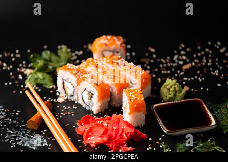 Die Auswahl verschiedener japanischer Sushi- und Brötchensorten. Auf dunklem rustikalem Hintergrund. Rollt auf dunklem Hintergrund. Meeresfrüchte mit Stäbchen. Nützlichkeit Stockfoto