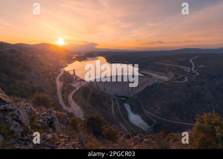 Blick auf den Arch Damm, umgeben von Hügeln und Bäumen im Atazar Reservoir von Madrid bei Sonnenuntergang Stockfoto