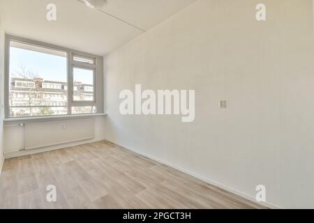 Innenausstattung eines hellen, leeren Raums mit Laminatboden und Fenster in Wohnwohnungen ohne Möbel Stockfoto