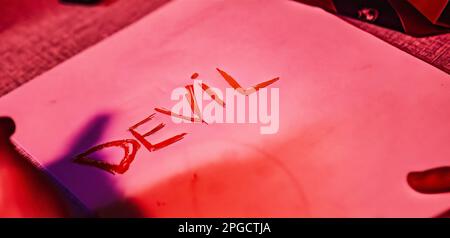 Nahaufnahme eines Papiers mit dem Wort „Teufel“ in kursiver Handschrift, wodurch eine geheimnisvolle und faszinierende Atmosphäre entsteht Stockfoto