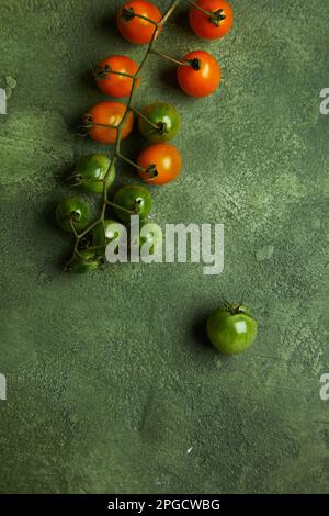Draufsicht auf einen Haufen frisch reifer und entreifender Kirschtomaten auf grünem Hintergrund Stockfoto